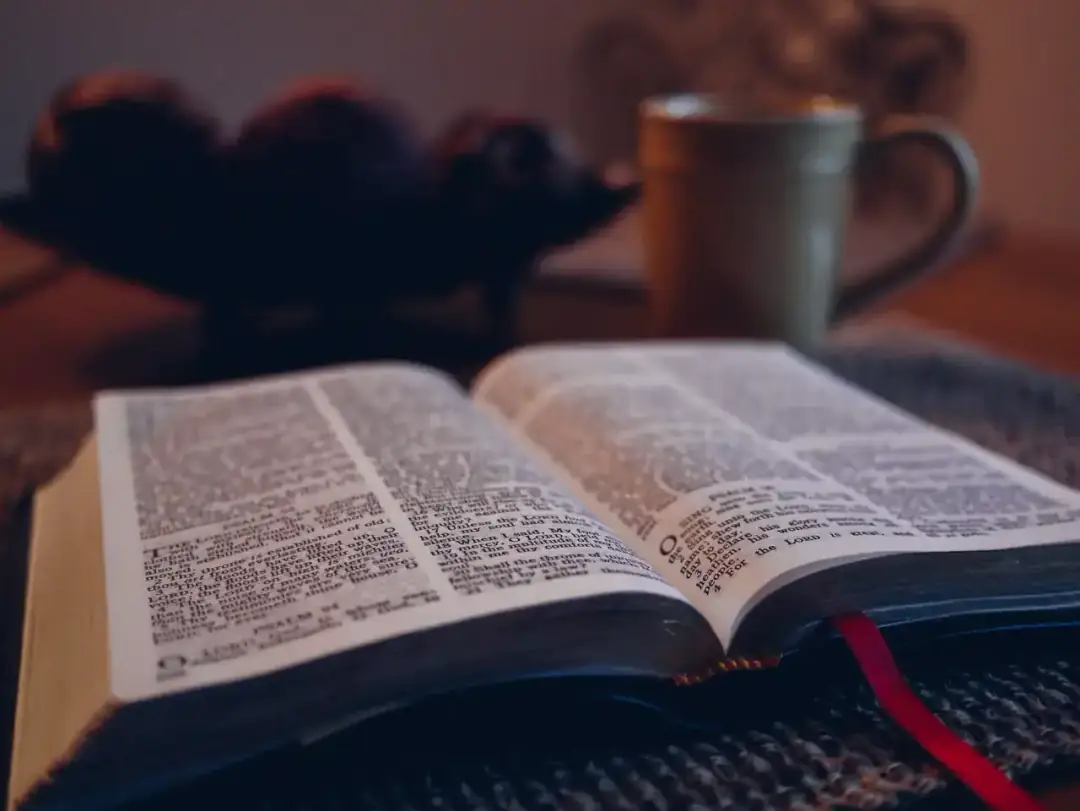 Una Biblia abierta sobre una mesa de madera, con luz cálida.