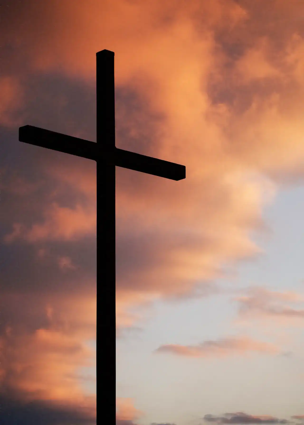 La silueta de una cruz contra un cielo de atardecer.