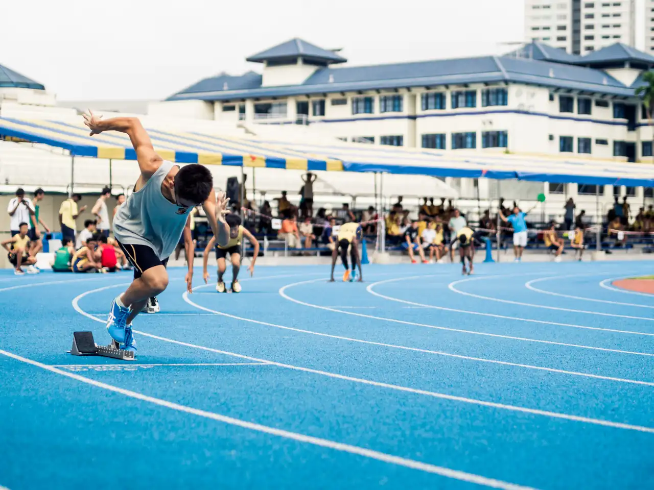 Un joven corre con fuerza por una pista atlética, al aire libre.